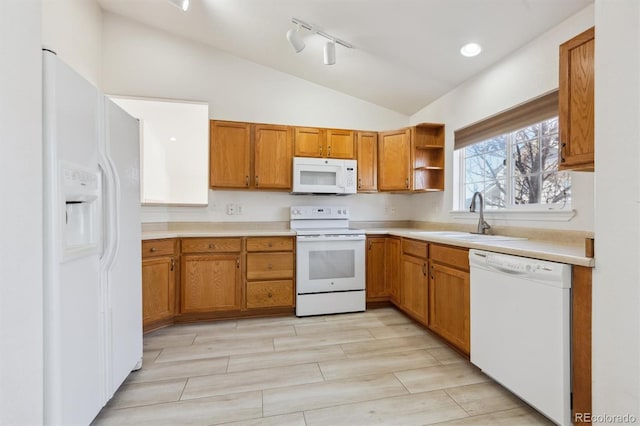 kitchen featuring rail lighting, white appliances, sink, and vaulted ceiling