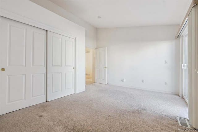 unfurnished bedroom featuring a closet and light colored carpet