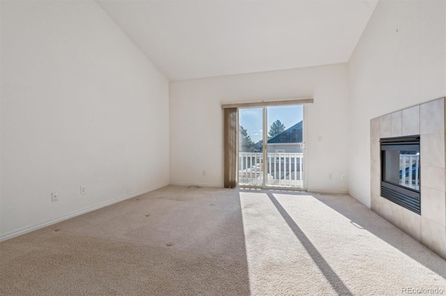 unfurnished living room with light colored carpet, lofted ceiling, and a tile fireplace