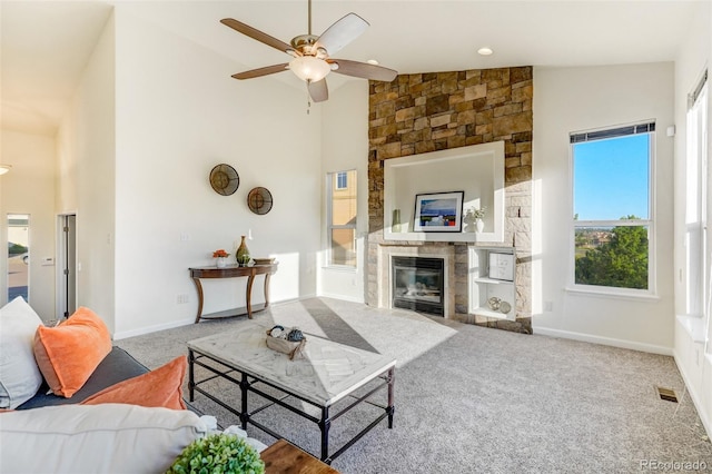 living room featuring a stone fireplace, ceiling fan, carpet, and high vaulted ceiling