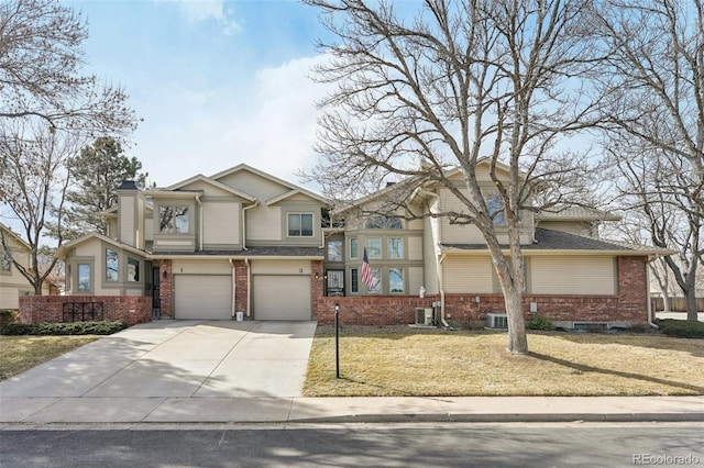 view of front of property with a shingled roof, concrete driveway, an attached garage, a front lawn, and brick siding