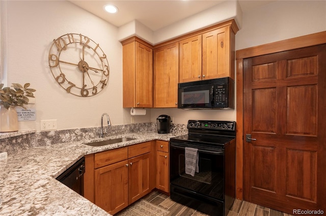 kitchen with sink, black appliances, light stone counters, and dark hardwood / wood-style flooring