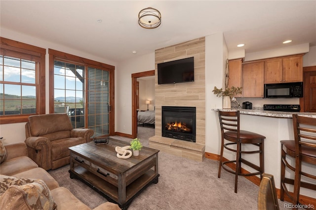 living room with a tile fireplace and carpet