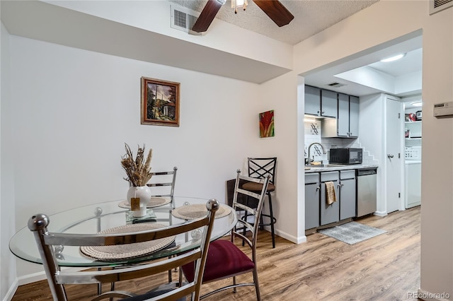 dining area featuring ceiling fan, washer / dryer, sink, light hardwood / wood-style flooring, and a textured ceiling