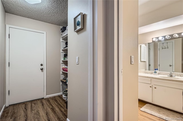 hall with wood-type flooring, sink, and a textured ceiling