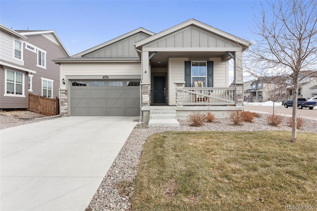 view of front facade with a garage, concrete driveway, stone siding, covered porch, and board and batten siding