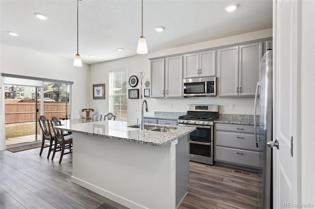 kitchen with stainless steel appliances, dark wood-style flooring, a sink, and gray cabinetry