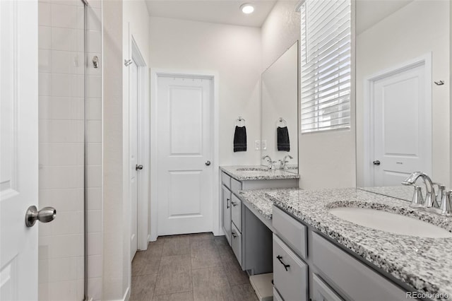 full bathroom featuring a tile shower, two vanities, a sink, and tile patterned flooring