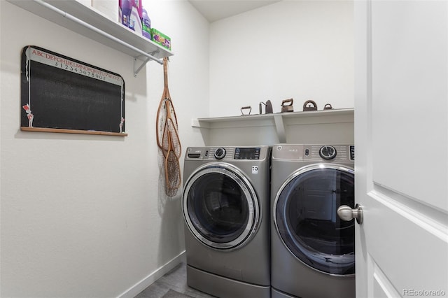 clothes washing area with washer and dryer, laundry area, baseboards, and wood finished floors