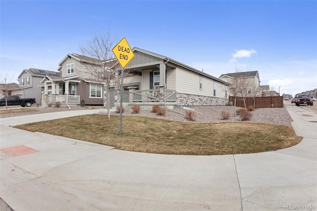 view of front of property featuring stone siding, a porch, and driveway