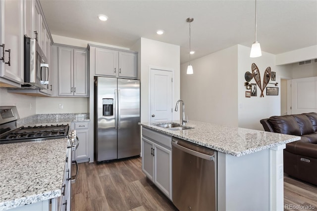 kitchen with dark wood finished floors, open floor plan, stainless steel appliances, gray cabinetry, and a sink