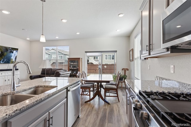 kitchen featuring light wood-style flooring, recessed lighting, a sink, appliances with stainless steel finishes, and pendant lighting