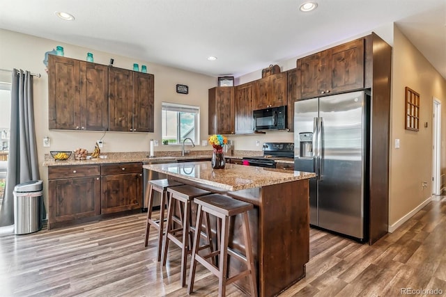 304 S 2nd Ave, Deer Trail, CO 80105 - kitchen with black appliances, wood finished floors, a kitchen island, dark brown cabinetry, and recessed lighting