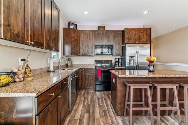 304 S 2nd Ave, Deer Trail, CO 80105 - kitchen with black appliances, a sink, a kitchen bar, dark wood finished floors, and dark brown cabinetry