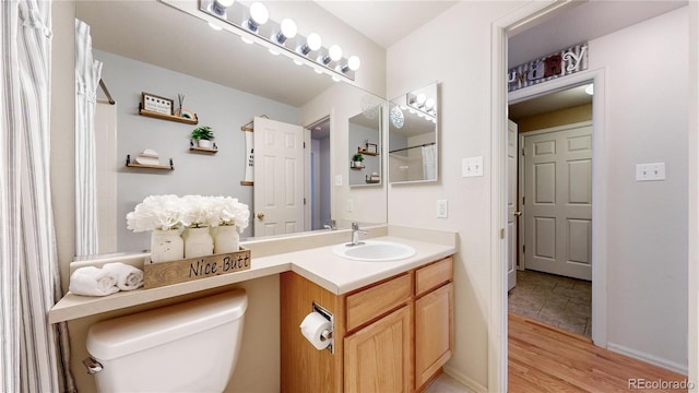 11560 River Run Cir, Commerce City, CO 80640 - full bath featuring wood finished floors, toilet, vanity, and baseboards