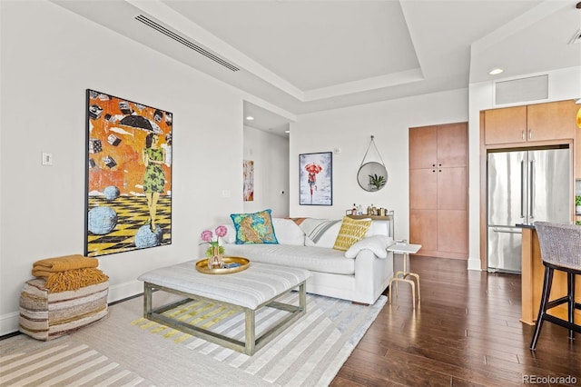 living room with wood-type flooring and a raised ceiling