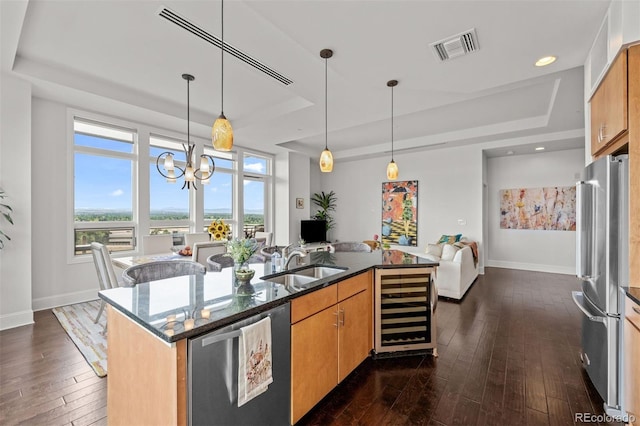 kitchen with a raised ceiling, wine cooler, a kitchen island with sink, and stainless steel appliances