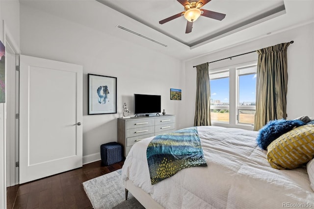 bedroom featuring ceiling fan, dark hardwood / wood-style floors, and a tray ceiling