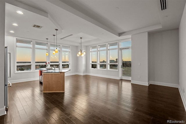 unfurnished living room featuring a notable chandelier, dark hardwood / wood-style flooring, and a tray ceiling