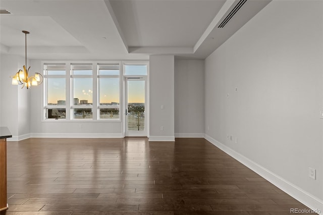 spare room featuring a tray ceiling, dark hardwood / wood-style floors, and a chandelier