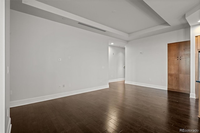 empty room featuring dark hardwood / wood-style flooring and a tray ceiling