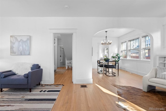 living room featuring light wood-type flooring and an inviting chandelier