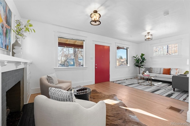 living room with a brick fireplace, hardwood / wood-style floors, and an inviting chandelier