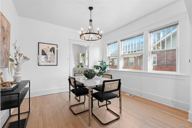 dining space with an inviting chandelier and light hardwood / wood-style flooring