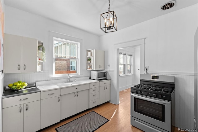 kitchen with hanging light fixtures, appliances with stainless steel finishes, sink, and white cabinetry