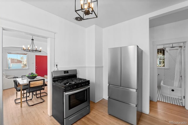 kitchen with a healthy amount of sunlight, a notable chandelier, stainless steel appliances, and light hardwood / wood-style floors