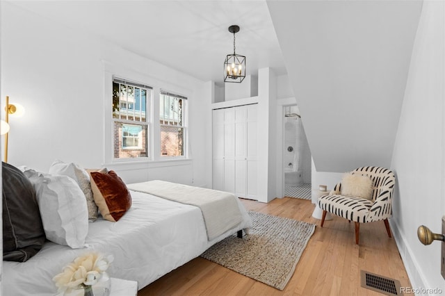 bedroom featuring a closet, light hardwood / wood-style floors, and an inviting chandelier