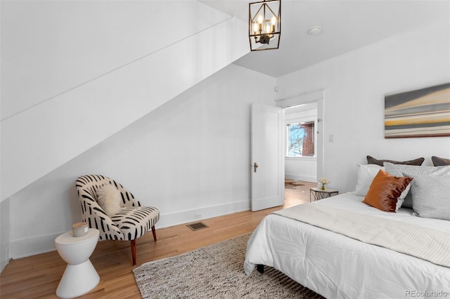 bedroom with light hardwood / wood-style flooring and an inviting chandelier