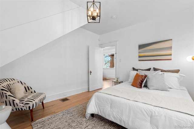 bedroom with hardwood / wood-style flooring and an inviting chandelier