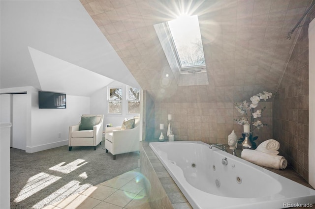 bathroom with a relaxing tiled tub, lofted ceiling with skylight, and tile patterned flooring