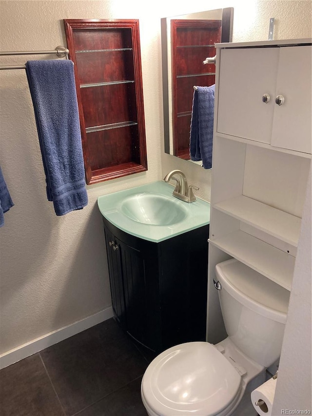 bathroom with tile patterned floors, vanity, toilet, baseboards, and a textured wall