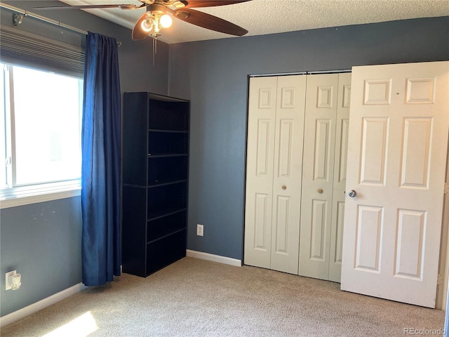 unfurnished bedroom with a closet, carpet flooring, baseboards, and ceiling fan