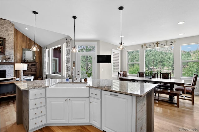 31189 Manitoba Dr, Evergreen, CO 80439 - kitchen featuring lofted ceiling, light stone countertops, white cabinetry, light wood finished floors, and an island with sink