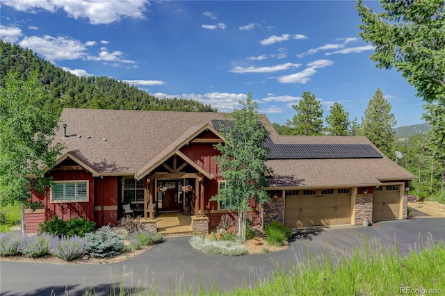 31189 Manitoba Dr, Evergreen, CO 80439 - view of front facade with stone siding, a garage, board and batten siding, a shingled roof, and asphalt driveway