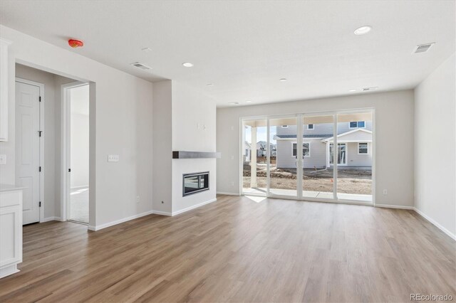 1300 Sienna Peak Cir, Erie, CO 80516 - unfurnished living room with a glass covered fireplace, light wood-style flooring, baseboards, visible vents, and recessed lighting