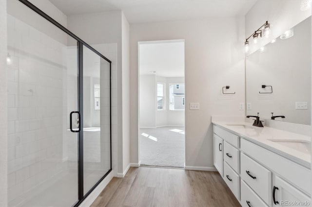 1300 Sienna Peak Cir, Erie, CO 80516 - bathroom with a stall shower, double vanity, wood finished floors, and a sink