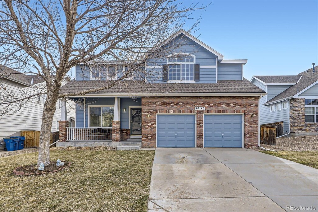 view of front facade featuring a front yard, driveway, a porch, an attached garage, and a shingled roof