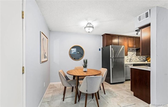 dining area with light marble finish floors, a textured ceiling, and baseboards