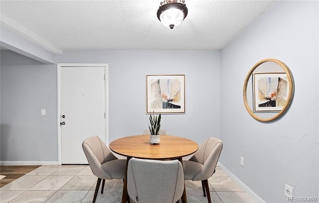 dining room featuring a textured ceiling and baseboards