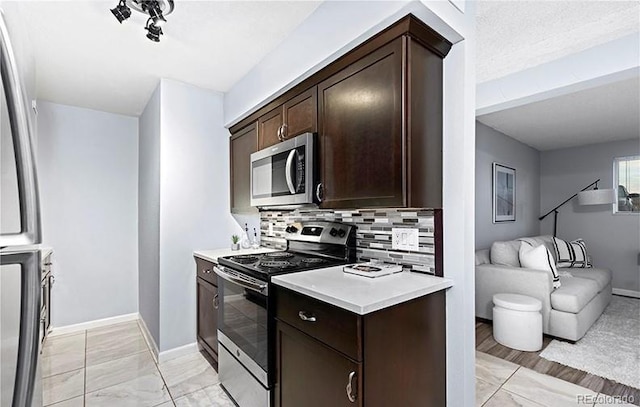 kitchen with appliances with stainless steel finishes, dark brown cabinetry, and light countertops