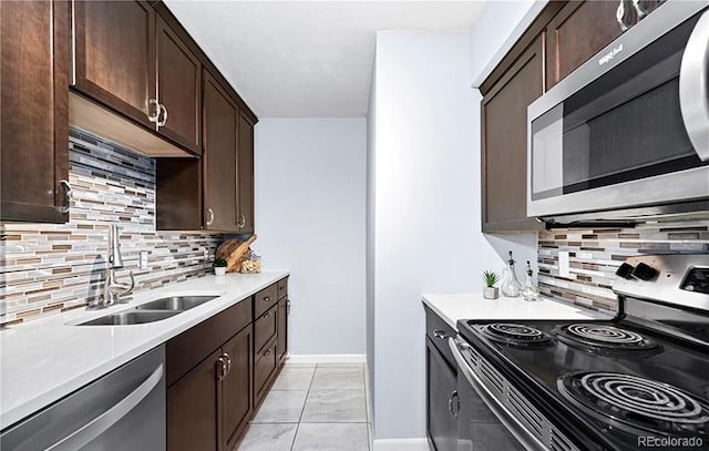 kitchen featuring stainless steel appliances, a sink, tasteful backsplash, and dark brown cabinets