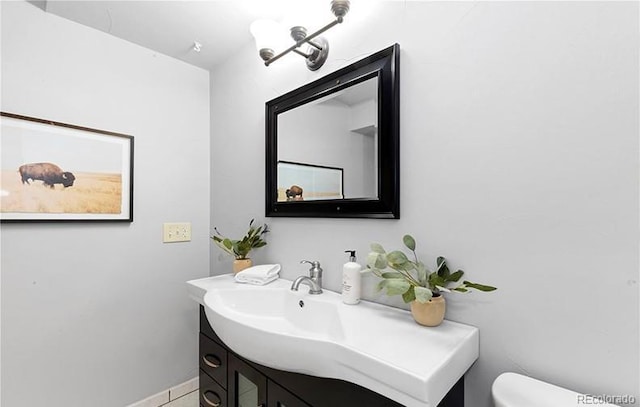 half bathroom with toilet, vanity, tile patterned flooring, and baseboards