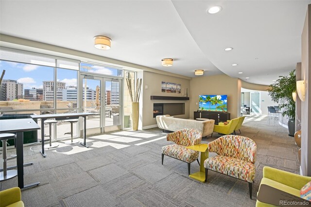 living room with a warm lit fireplace, french doors, recessed lighting, and a city view