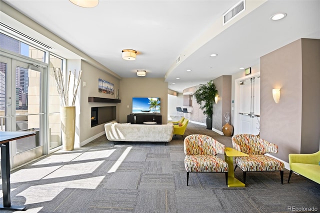 carpeted living area with recessed lighting, visible vents, baseboards, a lit fireplace, and french doors