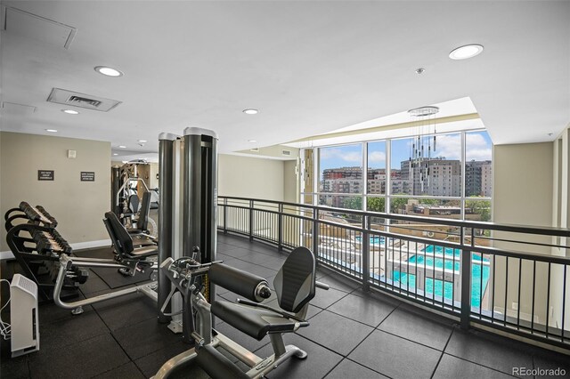 workout area with baseboards, visible vents, expansive windows, a view of city, and recessed lighting