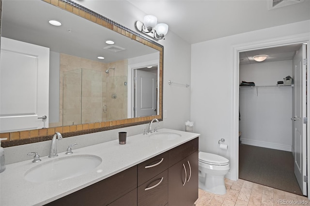 bathroom with double vanity, a stall shower, a sink, and toilet